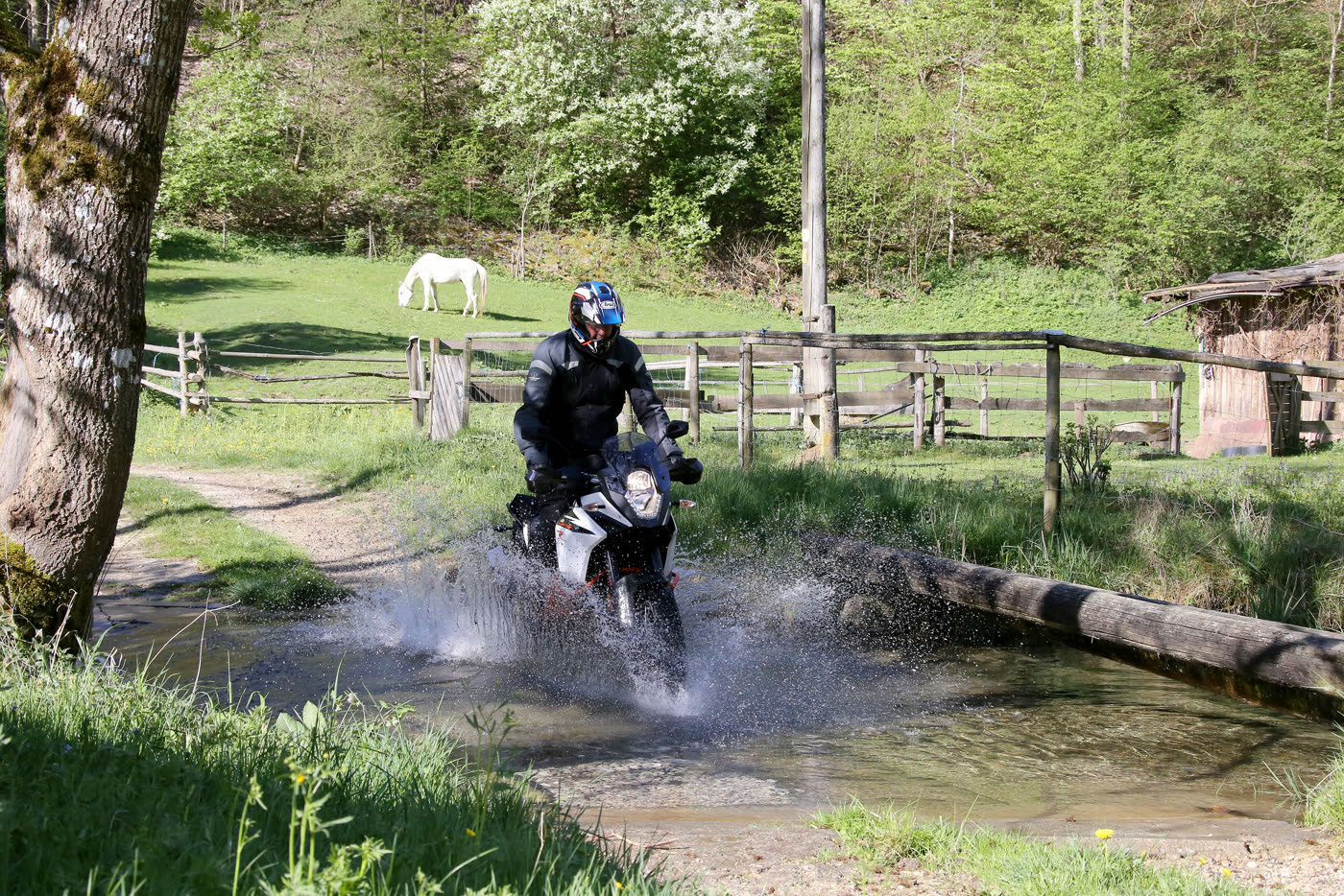 Motorrad durchfährt mit Gischt eine Furt bei Schelklingen