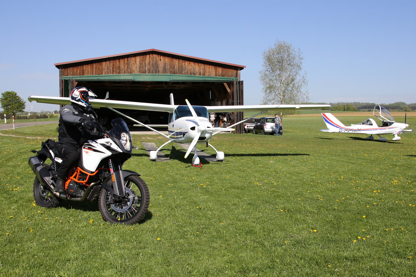 Motorrad vor abgestellten Segelflugzeugen auf dem ehemaligen Feldflugplatz Motorrad vor abgestellten Segelflugzeugen auf dem ehemaligen Feldflugplatz
